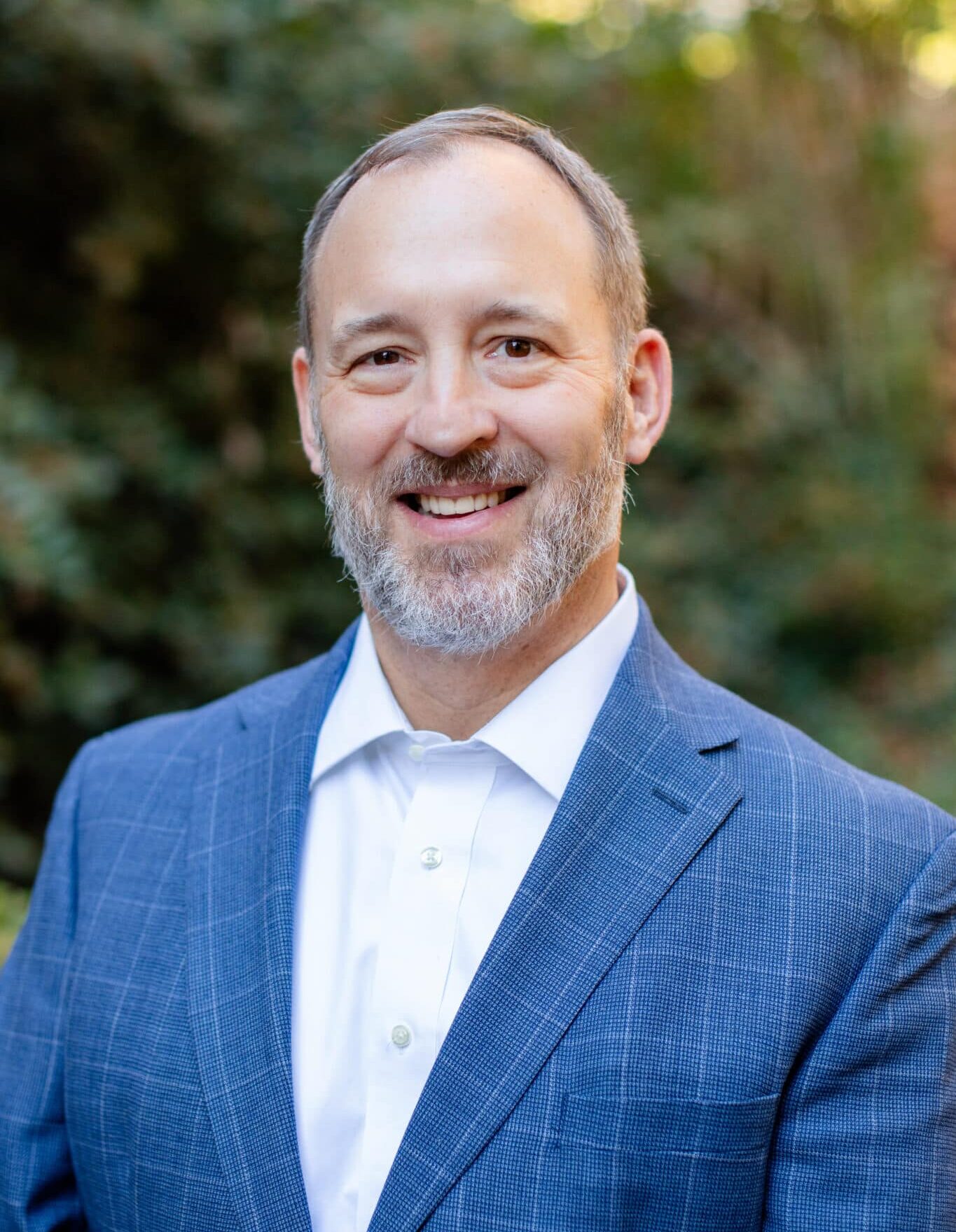 a man wearing a suit and tie smiling at the camera