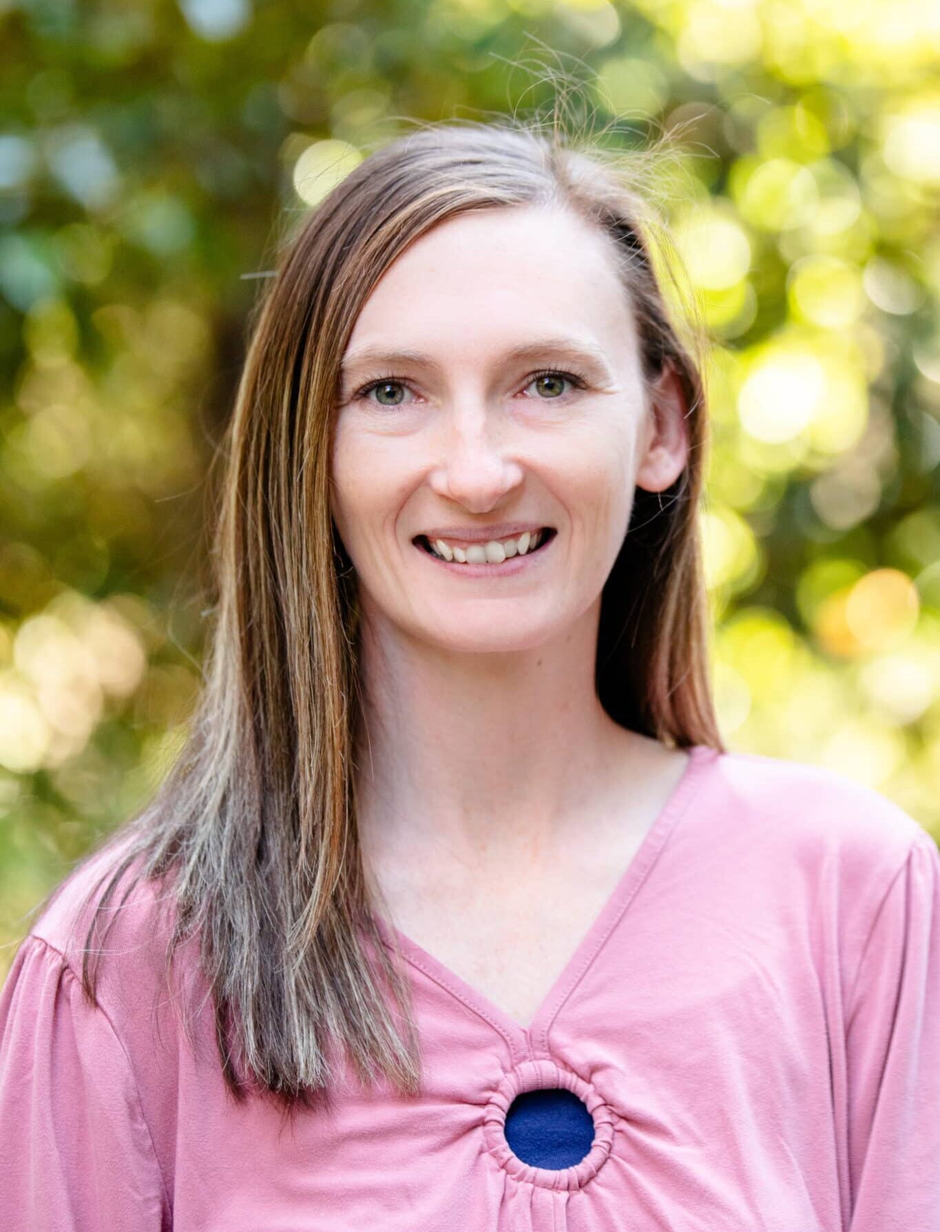 a woman wearing a purple shirt and smiling at the camera