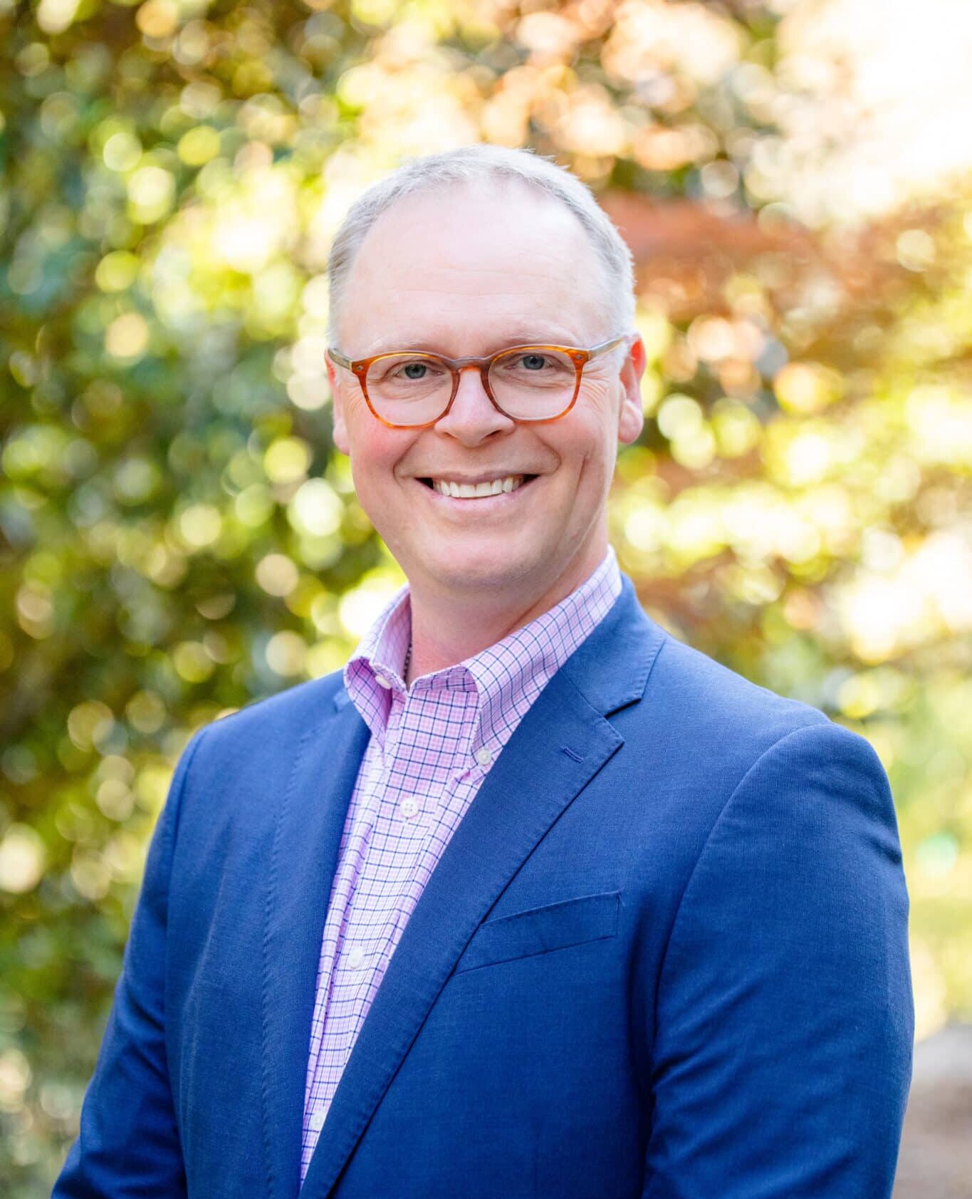 a man wearing glasses and smiling at the camera