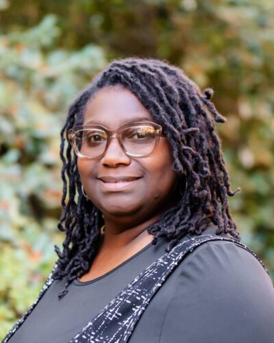 A Woman Wearing Glasses And Smiling At The Camera