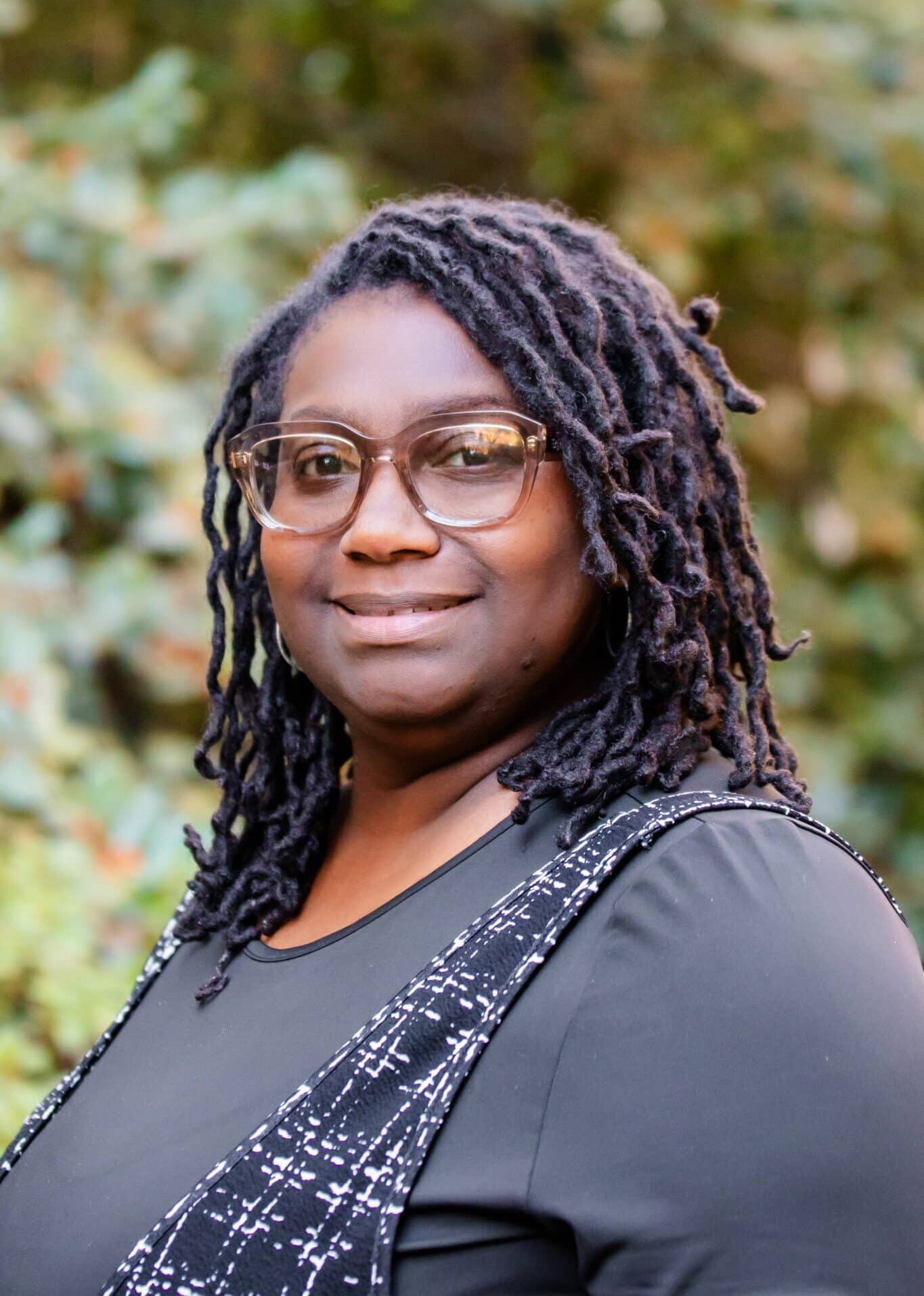 a woman wearing glasses and smiling at the camera