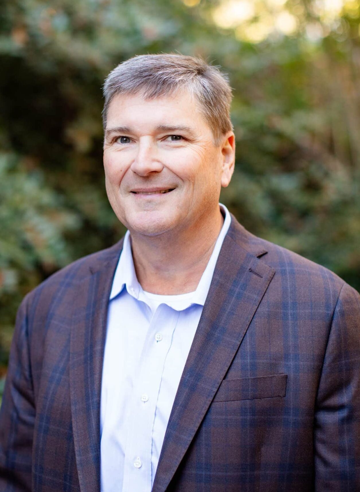 a man wearing a suit and tie smiling at the camera